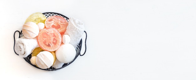 wall with soap, bath bombs and towel in basket on white wall copy space. Beauty and body care concept.