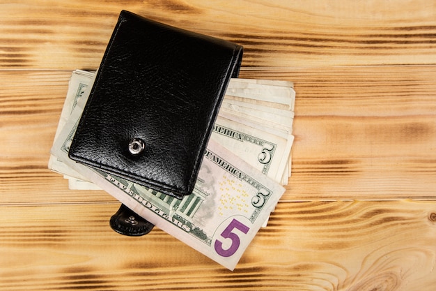 Wallet with money on wooden surface