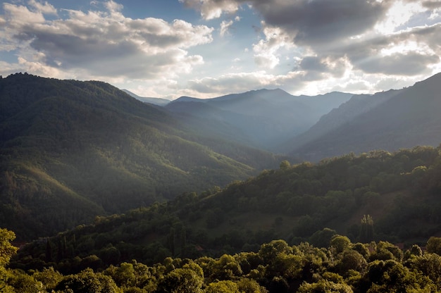 Wallpaper of sunset in the mountains with rays of light breaking through the clouds.