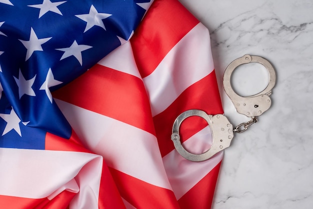 Wallpaper with the flag of the US next to handcuffs on a white marble base American judicial system