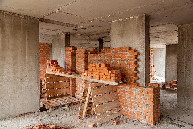 Walls of a multistorey red brick house Construction site tools wheel barrow sand and bricks