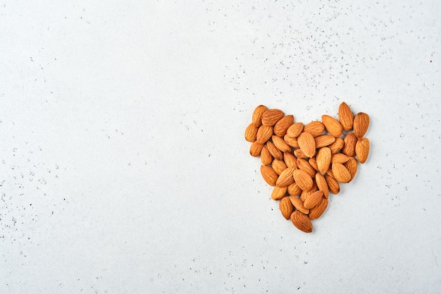 Walnut almonds laid out in the shape of a heart on white background.  Snack vegan sugarfree food.