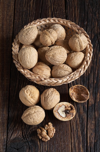 Walnut in bowl and walnuts kernels on old wooden table