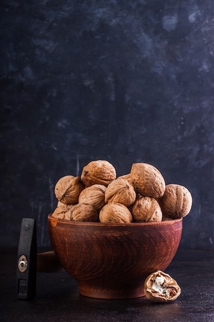 Walnut in a clay bowl and a gout on a concrete background. Copy space.