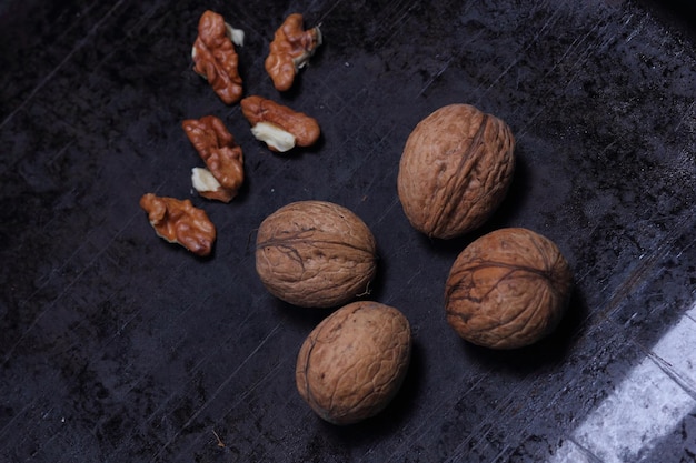 Walnut kernels and whole walnuts on a dark background Vegetarian food concept Closeup View from above