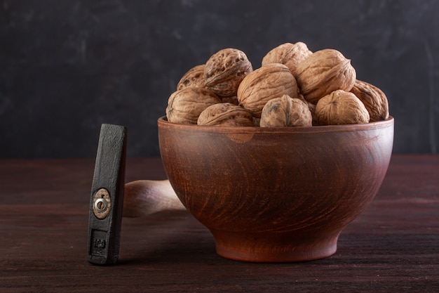 Walnut in pottery and hammer on a wooden table