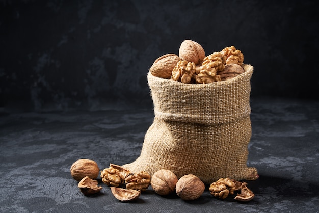 Walnuts  in bag on black table. Heap or stack of walnut.