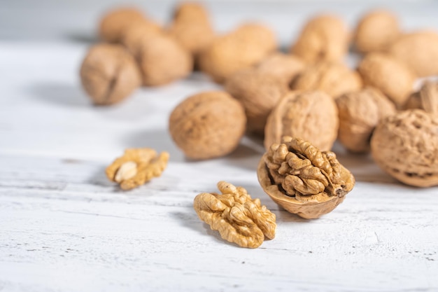 Walnuts kernels on white wooden desk. Pile of whole walnut shells