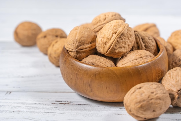 Walnuts kernels on white wooden desk. Whole walnut in wood vintage bowl.