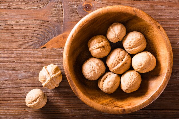 Walnuts in a plate and lie on a wooden table. Top view