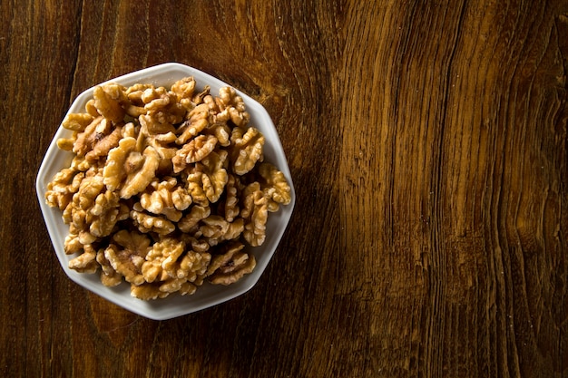 walnuts in white bowl on wood table.