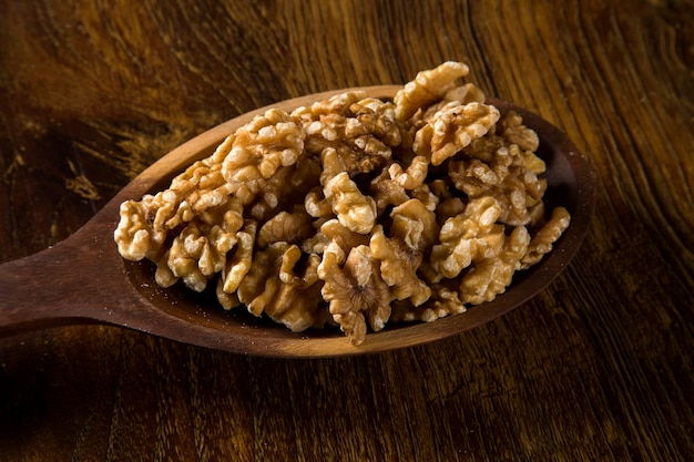 walnuts in wood spoon on wood table.