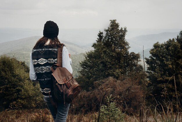 Photo wanderlust and travel concept with space for text hipster traveler looking at woods on top of mountains amazing view stylish woman hiking atmospheric moment