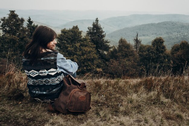 Photo wanderlust and travel concept with space for text hipster traveler looking at woods on top of mountains amazing view stylish woman hiking atmospheric moment