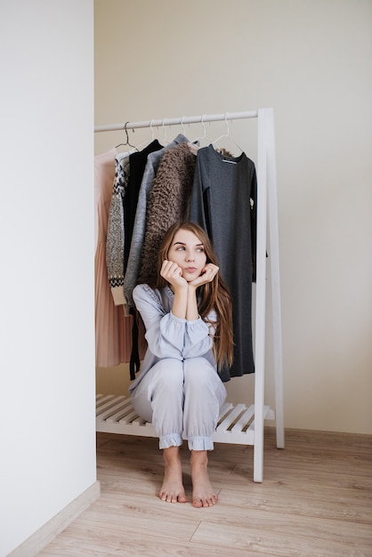 Photo wardrobe of a young girl. dresses on hangers. flour choice. what to wear? a girl in pajamas does not know what to wear.