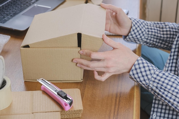 Warehouse employee packs the order of the online store in a cardboard box