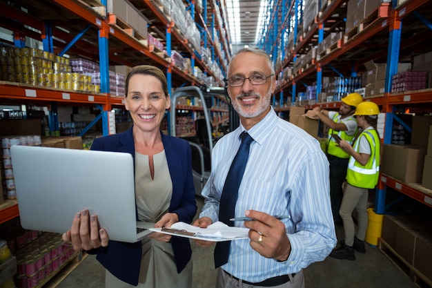 Warehouse manager and client holding digital tablet and clipboard