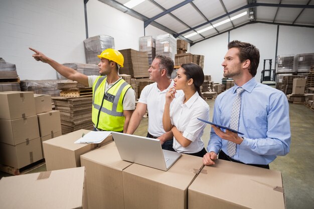 Warehouse worker pointing something to his colleagues