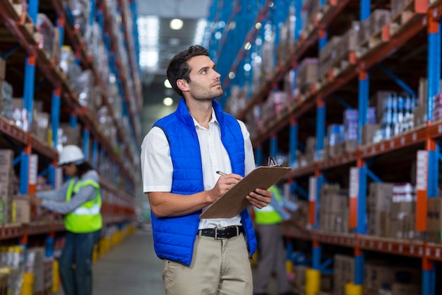 Warehouse worker writing on clipboard