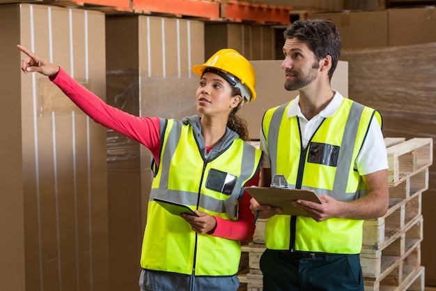 Warehouse workers discussing with clipboard and digital tablet