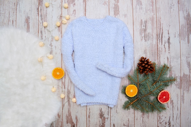 Warm blue sweater spruce twigs, oranges and festive garland