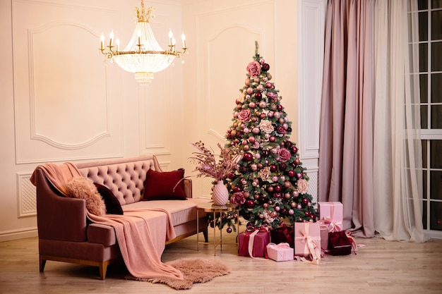 Warm cozy beautiful modern room design in gentle light colors decorated with a Christmas tree and decor elements for the new year