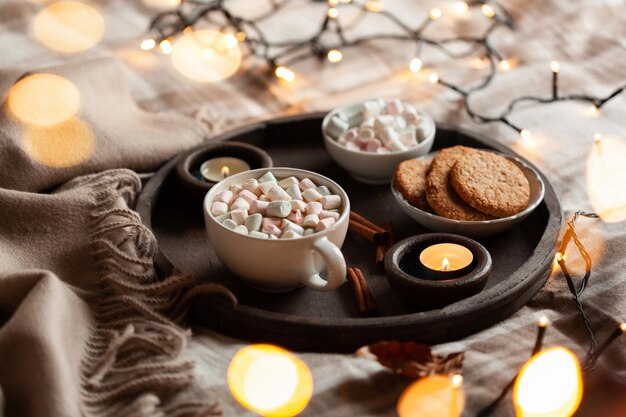 Photo warm cozy bedroom interior with cup of hot chocolate on tray candles christmas lights