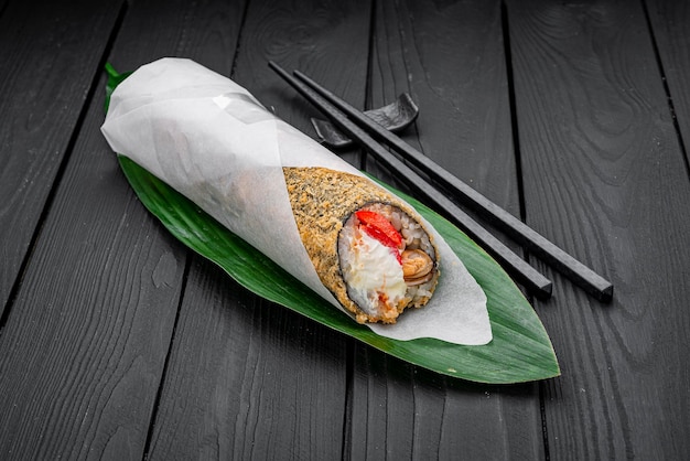 Warm hand roll with mussels peppers and cream cheese on a dark background