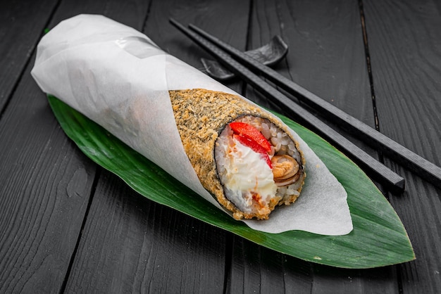 Warm hand roll with mussels peppers and cream cheese on a dark background