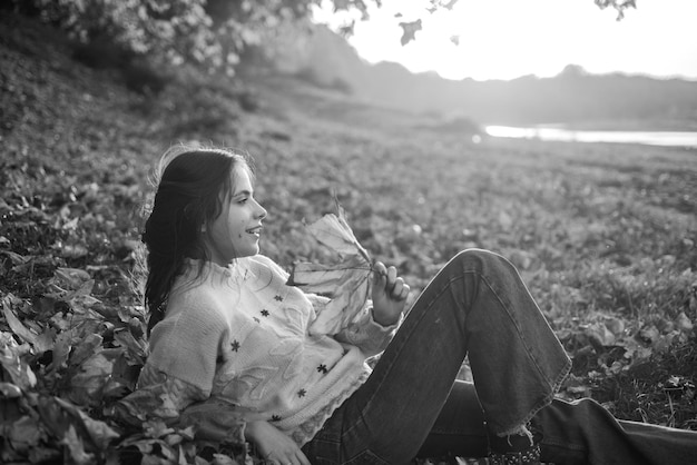 Warm moments of autumn Woman pretty girl enjoy autumn Girl relaxed lay fallen leaves on sunny autumn day Warmth and coziness Female autumn leaves background Catching evening sunbeams