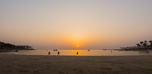 Warm orange sun at the sunrise with snorkelers on the beach in egypt panorama