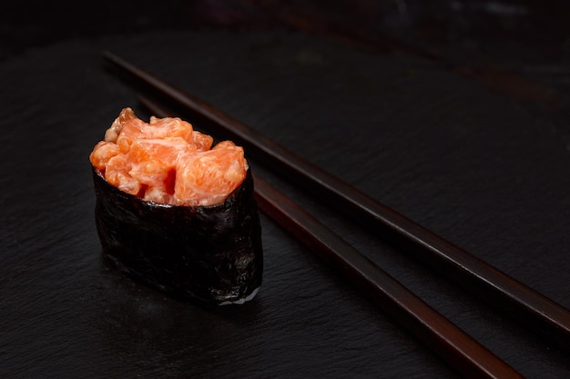 Warm rolls with tuna salmon perch eel tobiko caviar nori rice cucumber on black background