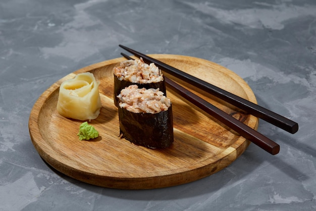 Warm rolls with tuna salmon perch eel tobiko caviar nori rice cucumber on wooden board gray stone background