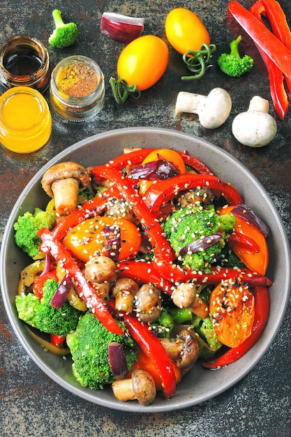 Warm salad with broccoli, mushrooms and red paprika. Vegan bowl with warm vegetables on a stylish shabby background. Healthy food. Fitness lunch with mushrooms and vegetables.