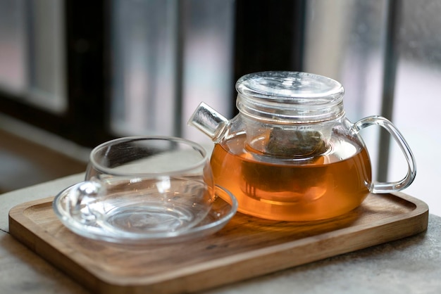 Warm tea in a teapot and cup on a wooden tray