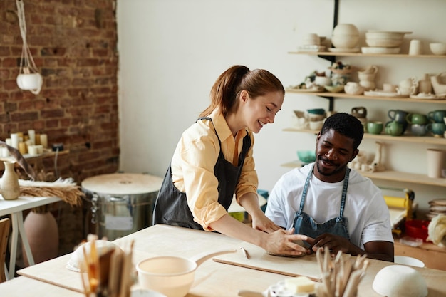 Warm toned portrait of smiling multirational couple making handmade ceramics in pottery studio toget