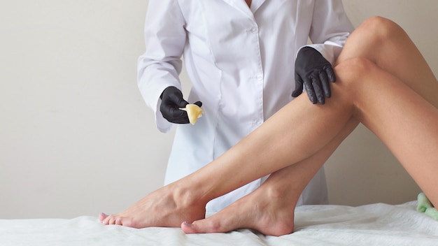 Warm wax on women's feet, professional depilation hair removal in the Studio