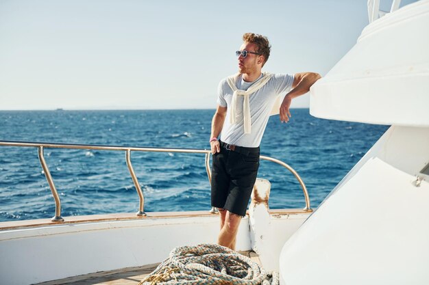 Warm weather Young male tourist is on the yacht on the sea Conception of vacation