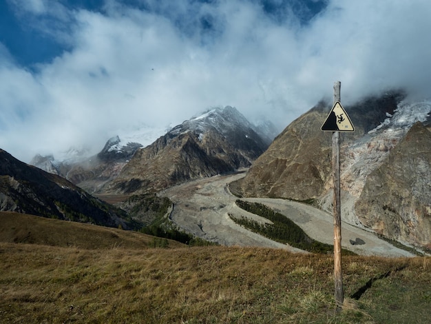 A warning sign of a possible fall from the mountain against the background of a beautiful mountain