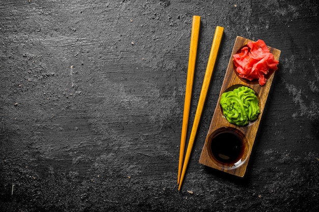 Photo wasabi marinated ginger and soy sauce in a wooden stand with chopsticks