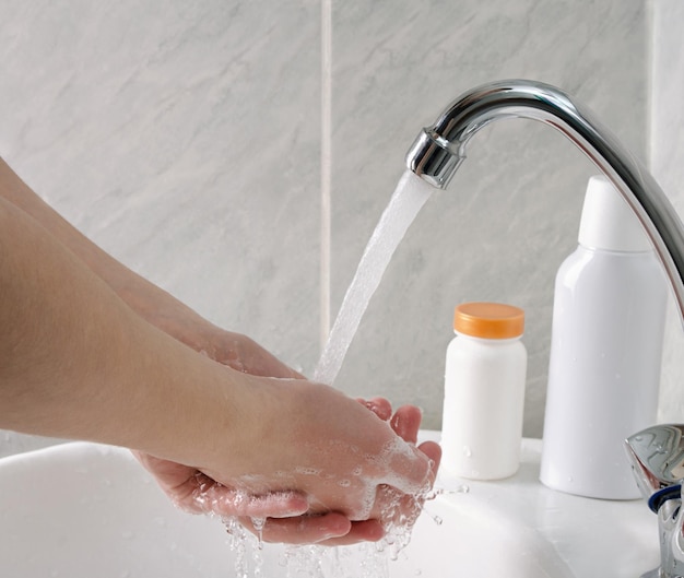 Wash hands with soap and tap water in bathroom as protection against bacteria flu