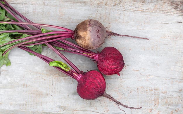 Washed red beets with tops cut in half put on a wooden countertoptop view