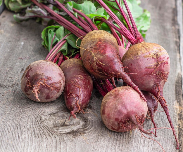 Washed red dining room beetroot with tops top view on a wooden table