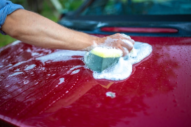 washing the car by hand with a sponge and shampoo the car is red