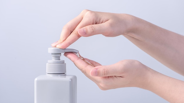 Washing hands Asian young woman using liquid soap to wash hands concept of hygiene to protective pandemic coronavirus isolated on gray white background close up