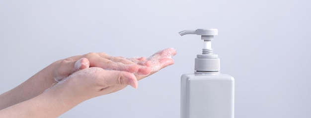 Washing hands Asian young woman using liquid soap to wash hands concept of hygiene to protective pandemic coronavirus isolated on gray white background close up