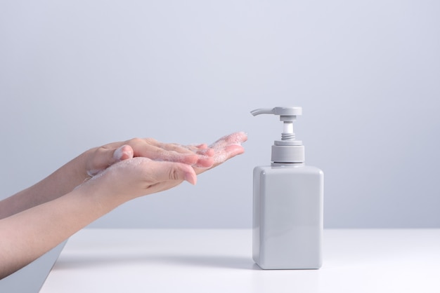 Washing hands. Asian young woman using liquid soap to wash hands, concept of hygiene to stop spreading coronavirus isolated on gray white background, close up.