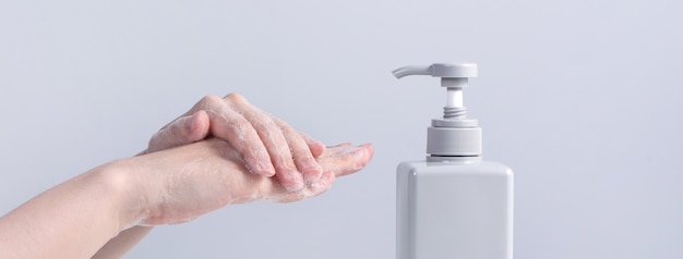 Washing hands. Asian young woman using liquid soap to wash hands, concept of hygiene to stop spreading coronavirus isolated on gray white background, close up.