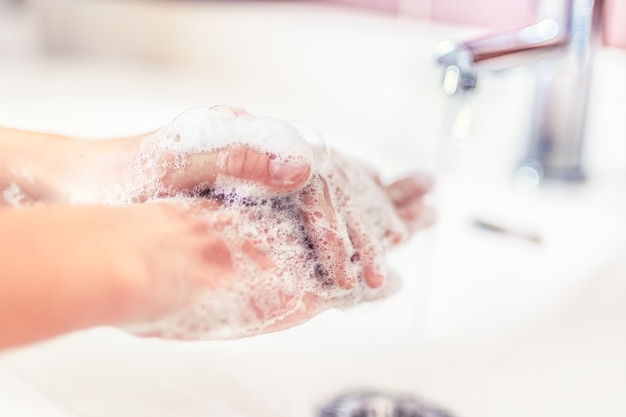 Washing hands with water and liquid soap in the bathroom. Hygiene anti-virus concept.