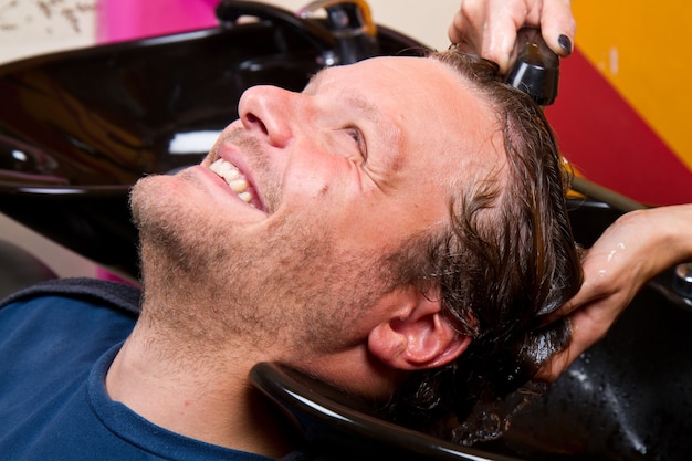 Washing man hair in beauty parlour hairdressing salon